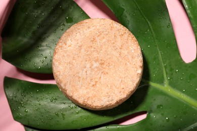 Photo of Solid shampoo bar and leaf on pink background, top view. Hair care
