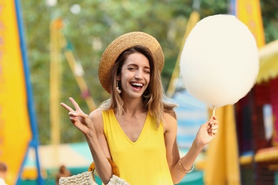 Photo of Happy young woman with cotton candy in amusement park