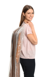 Young woman holding hanger with dress in plastic bag on white background. Dry-cleaning service