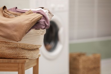 Photo of Laundry basket filled with clothes on chair in bathroom, closeup. Space for text