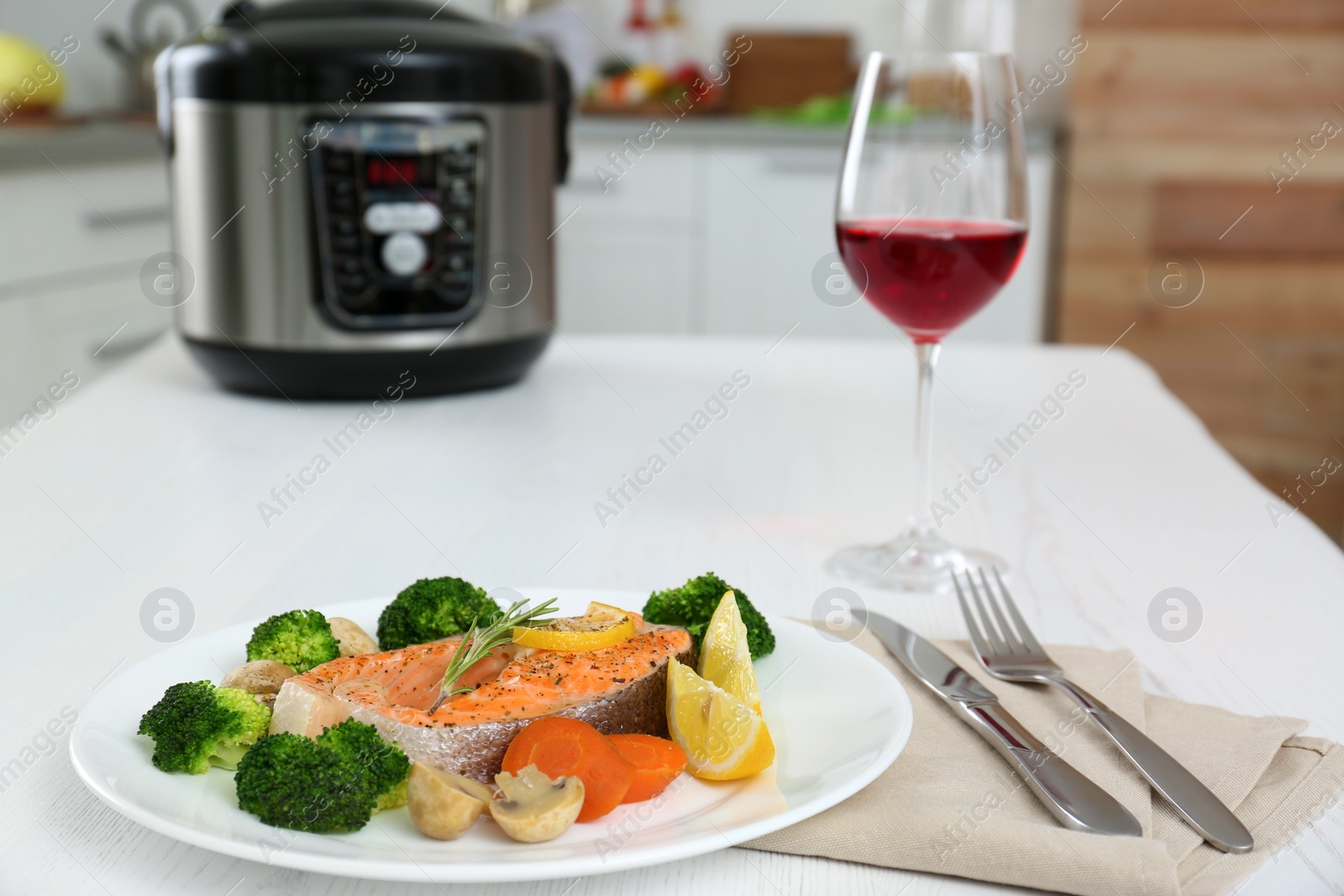 Photo of Plate with salmon steak and garnish prepared in multi cooker on table