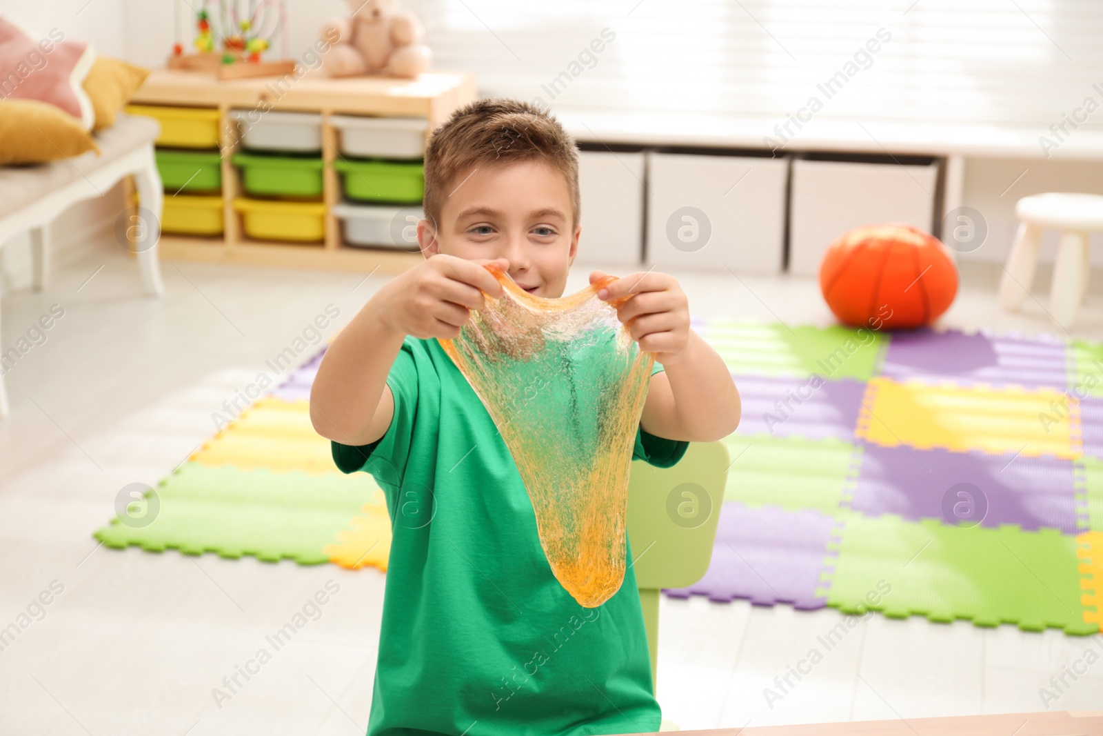 Photo of Little boy playing with slime in room