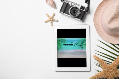 Tablet with travel blogger's stuff on white background, top view