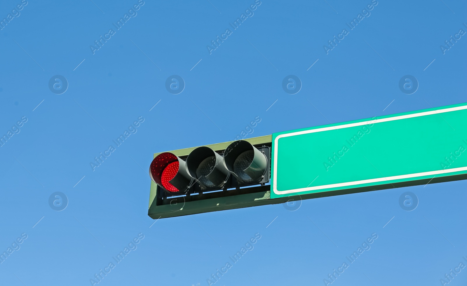 Photo of Traffic light against blue sky. Road rules