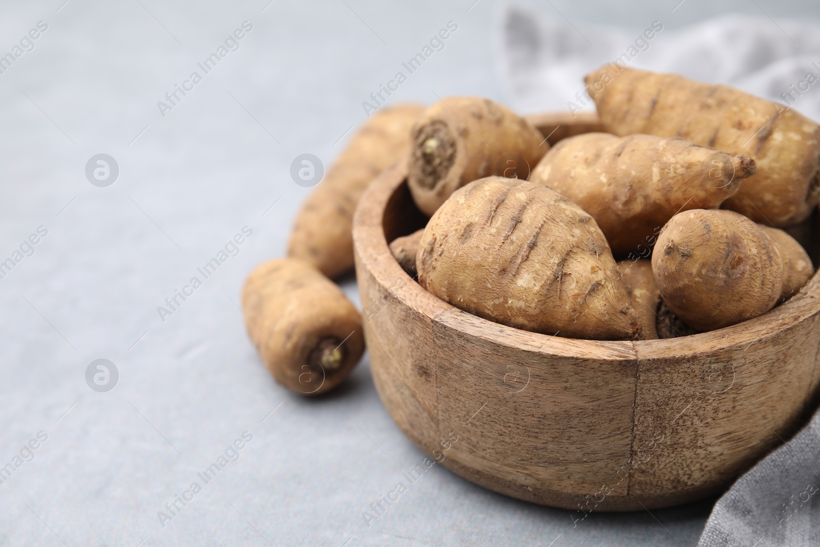 Photo of Tubers of turnip rooted chervil on light grey table, closeup. Space for text