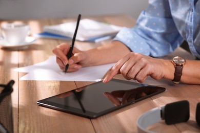 Photo of Woman with modern tablet learning at table indoors, closeup