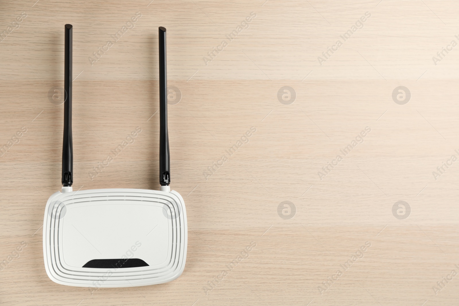 Photo of Modern Wi-Fi router on wooden background, top view. Space for text