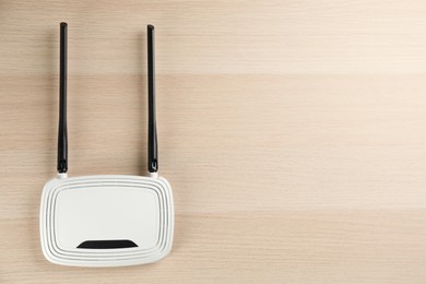 Photo of Modern Wi-Fi router on wooden background, top view. Space for text