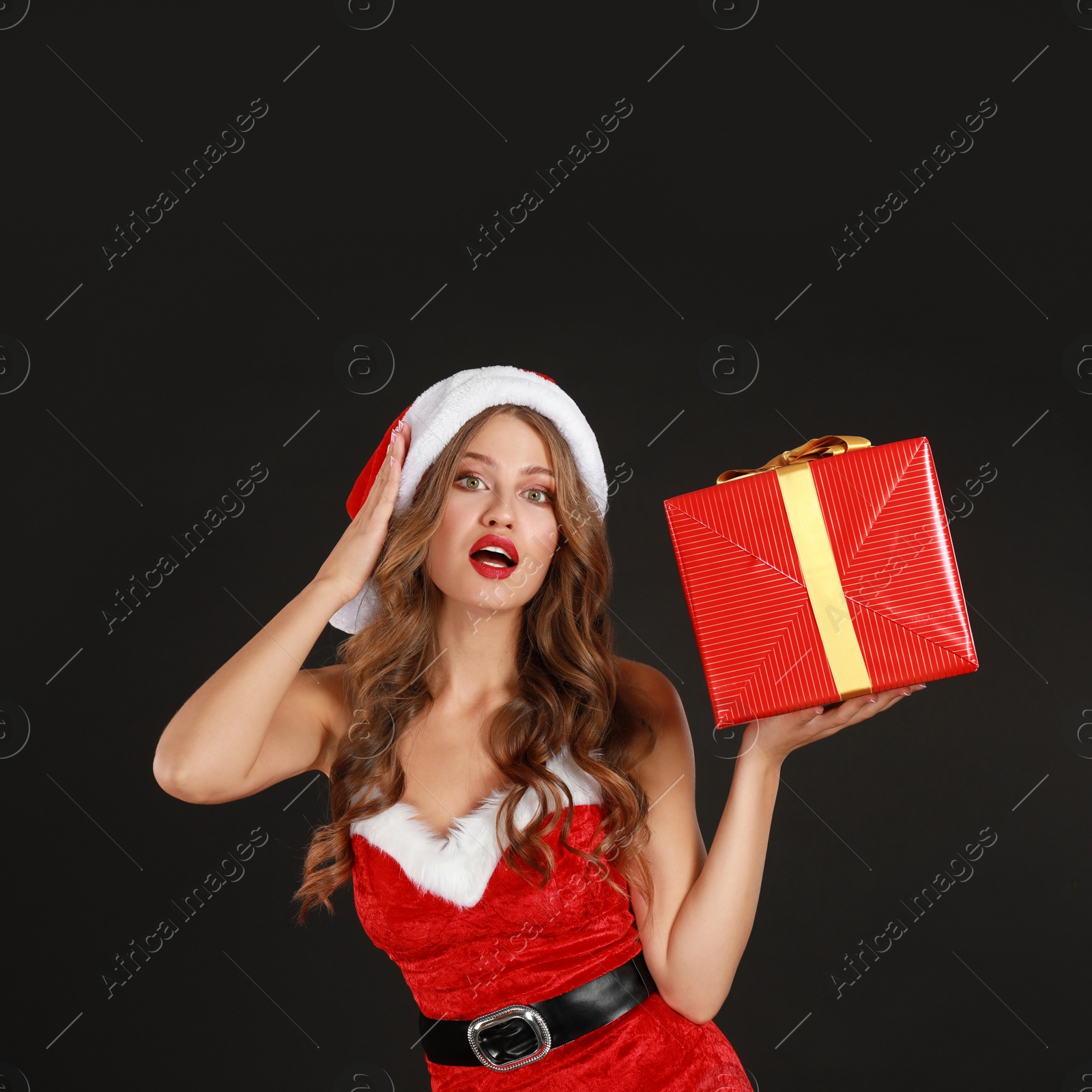 Photo of Beautiful Santa girl with Christmas gift on black background
