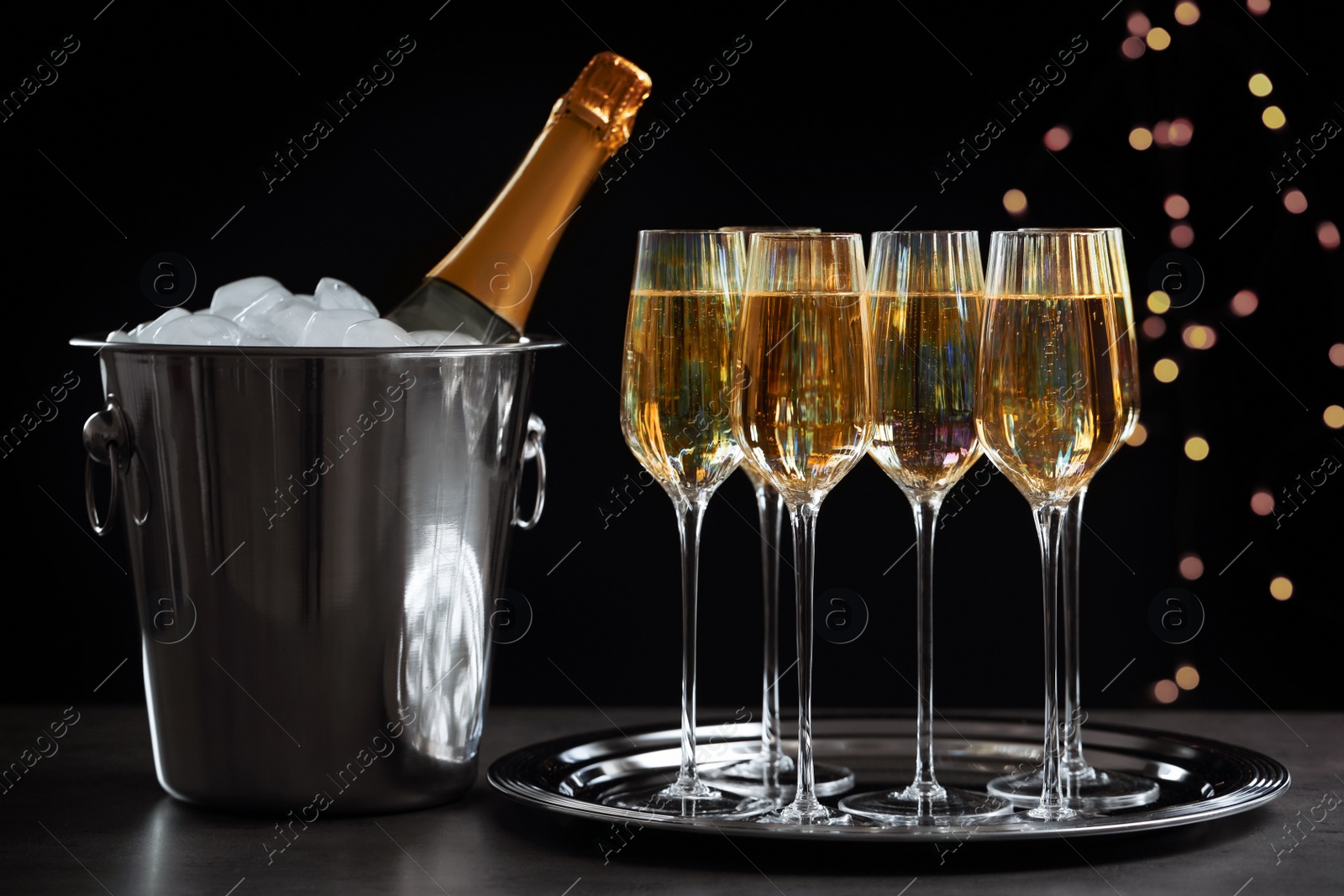 Photo of Glasses of champagne and ice bucket with bottle on grey table