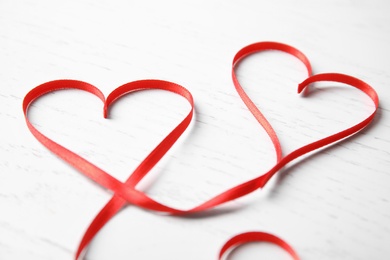 Hearts made of red ribbon on white wooden background. Valentine's day celebration