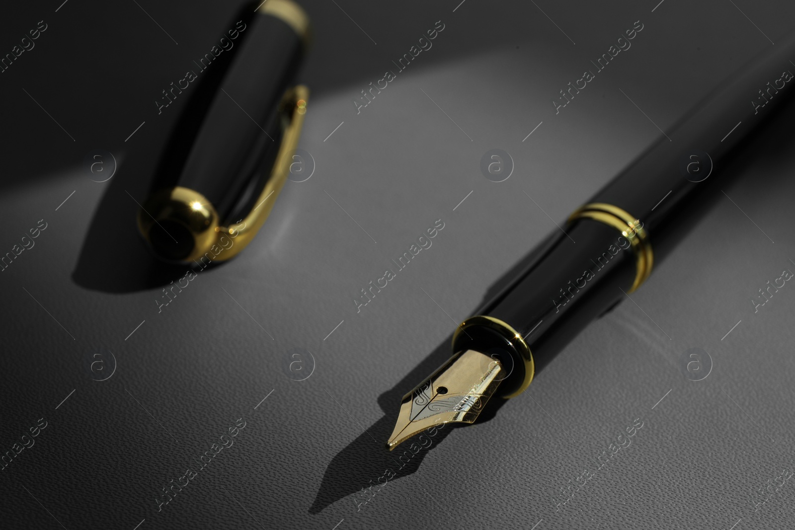 Photo of Stylish fountain pen on light grey textured table, closeup