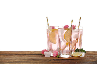 Photo of Delicious refreshing drink with rose flowers and lemon slices on wooden table against white background. Space for text