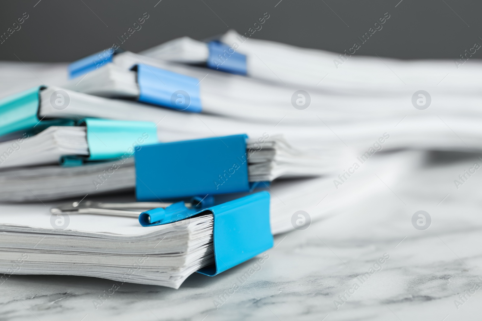 Photo of Stack of documents with binder clips on marble table, closeup