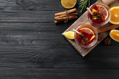 Photo of Aromatic punch drink and ingredients on black wooden table, flat lay. Space for text