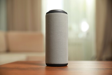 Photo of Portable bluetooth speaker on wooden table indoors. Audio equipment