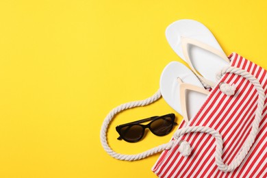 Photo of Flat lay composition with bag and other beach accessories on yellow background. Space for text
