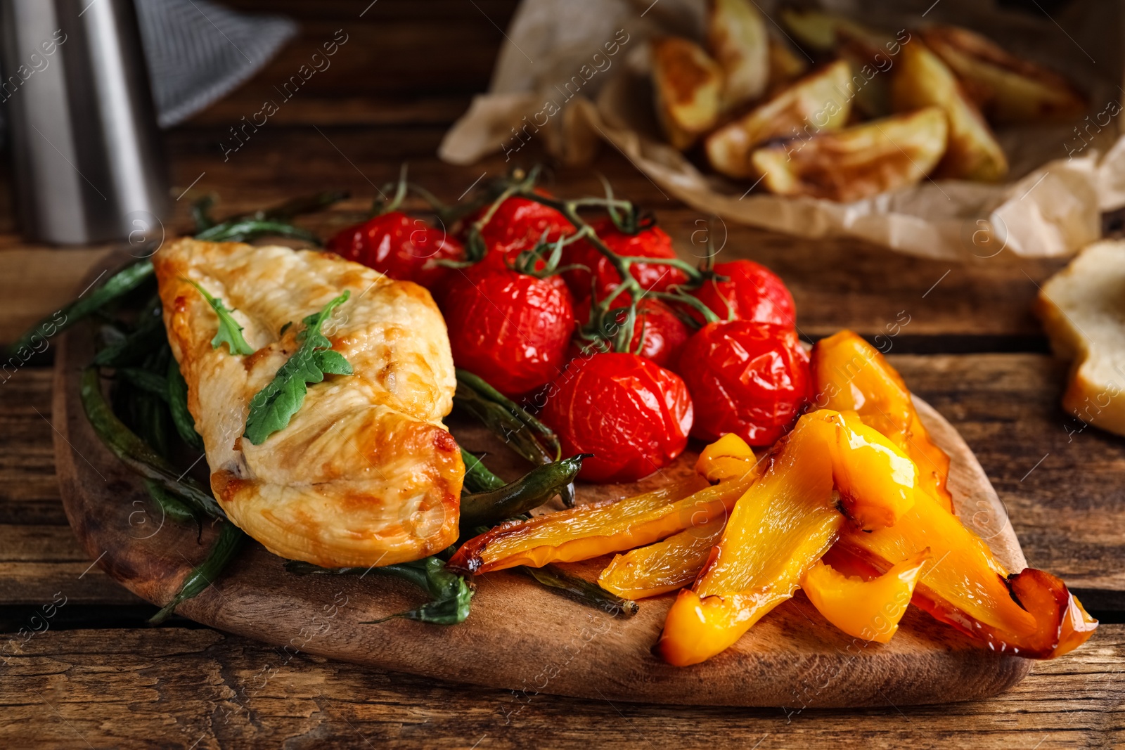 Photo of Delicious cooked chicken and vegetables on wooden table, closeup. Healthy meals from air fryer