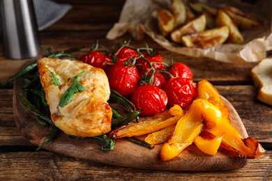 Delicious cooked chicken and vegetables on wooden table, closeup. Healthy meals from air fryer