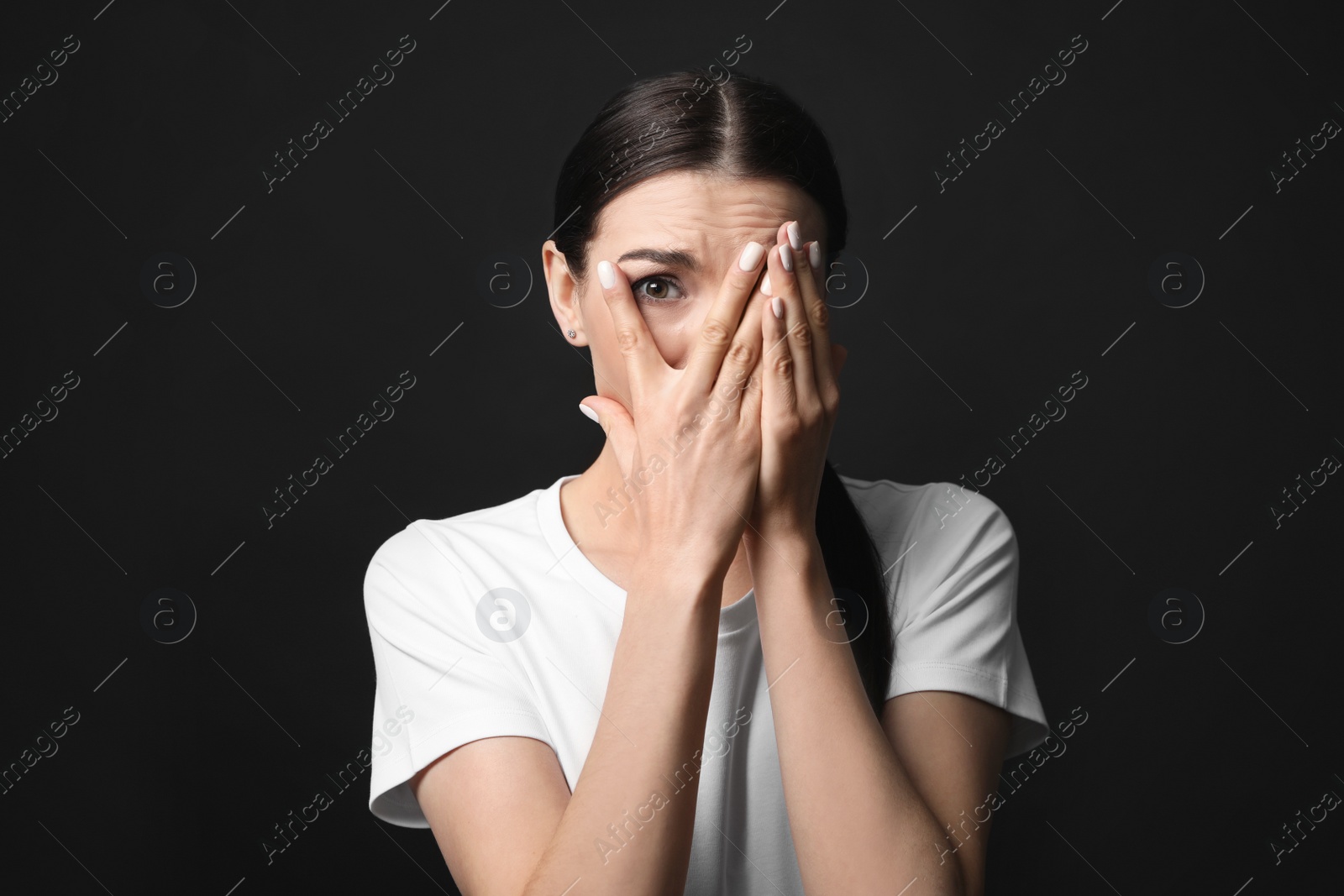 Photo of Young woman feeling fear on black background