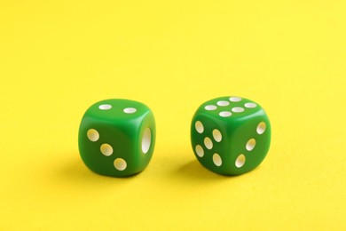 Photo of Two green game dices on yellow background, closeup