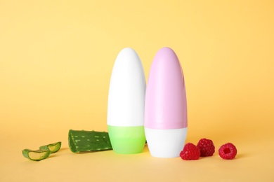 Photo of Female roll-on deodorants, aloe and raspberries on light orange background