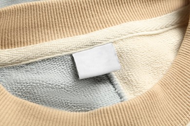 Photo of Blank clothing label on stylish sweater, closeup
