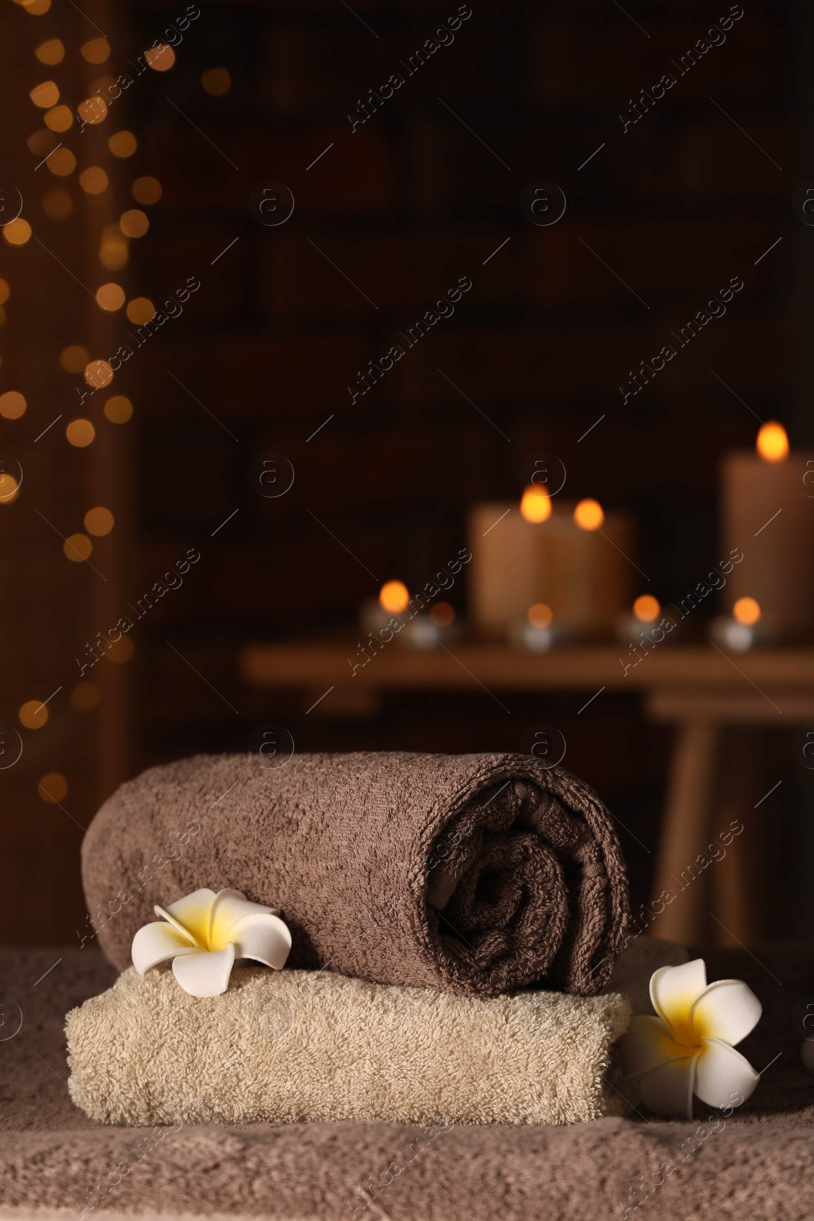 Photo of Spa composition with towels and plumeria flowers on massage table in wellness center