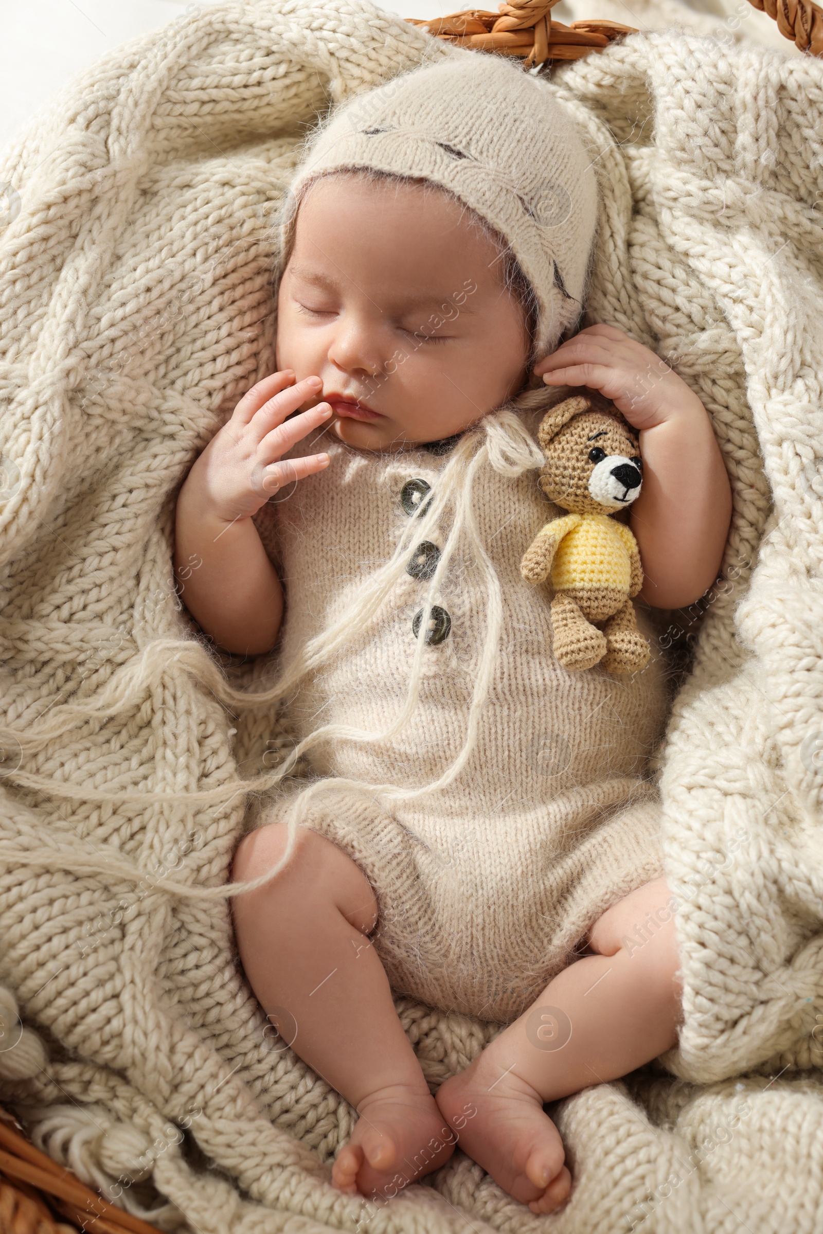 Photo of Adorable newborn baby with toy bear sleeping in wicker basket, top view