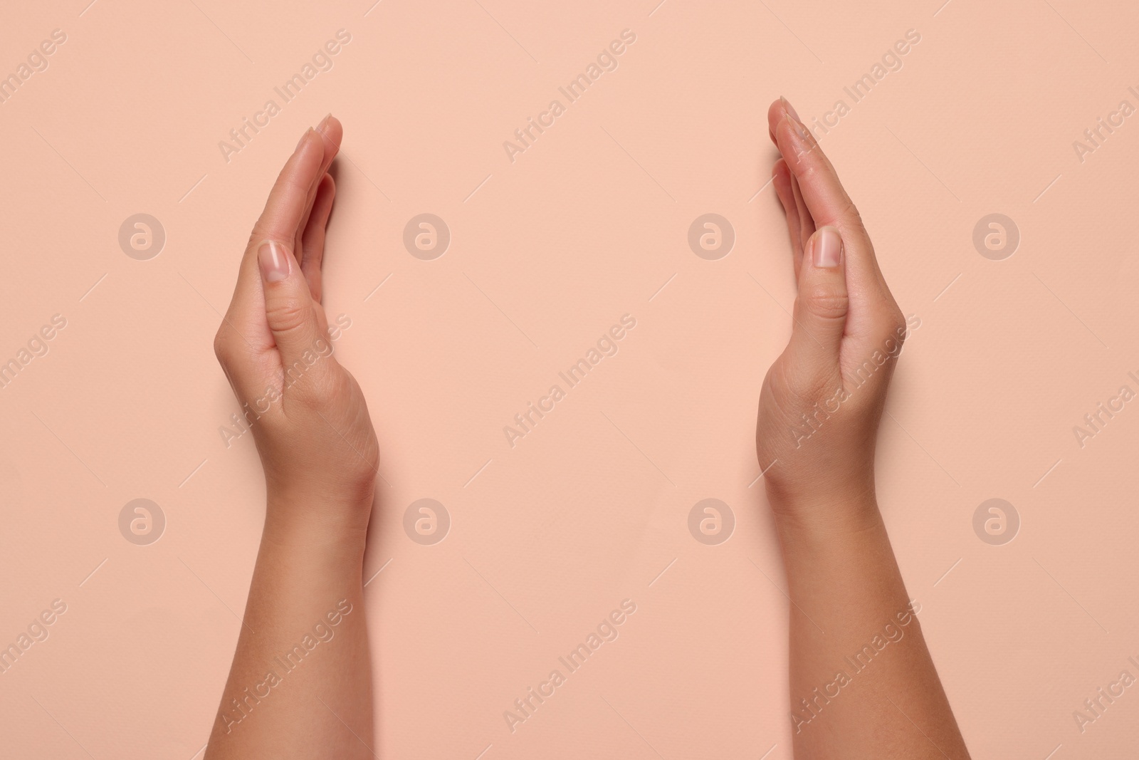 Photo of Woman holding on pale pink background, closeup of hands. Space for text