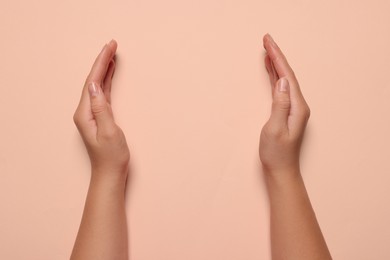Photo of Woman holding on pale pink background, closeup of hands. Space for text