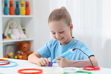 Girl drawing with stylish 3D pen at white table indoors