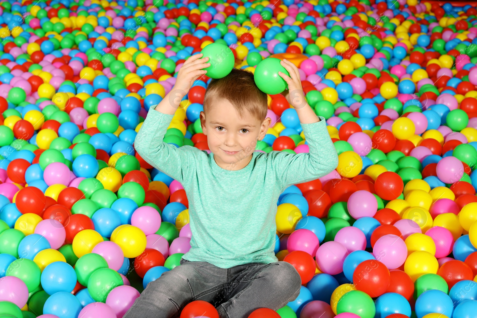 Photo of Cute child playing in ball pit indoors