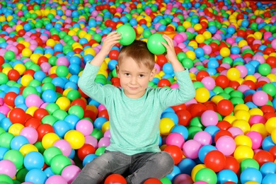 Photo of Cute child playing in ball pit indoors