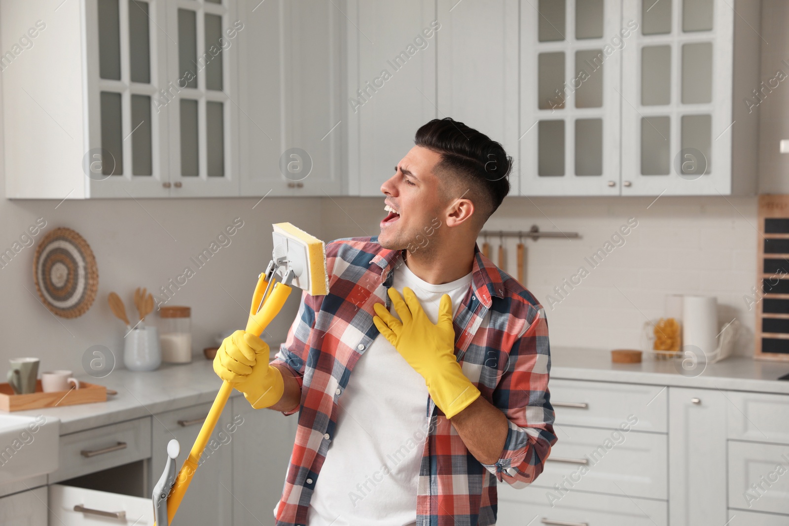 Photo of Man with mop singing while cleaning at home