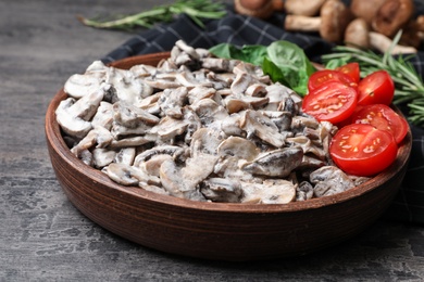 Wooden plate with delicious cooked mushrooms on grey table, closeup