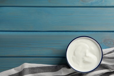 Photo of Bowl of tasty yogurt on light blue wooden table, top view. Space for text