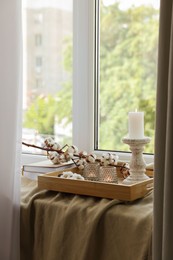 Photo of Beautiful candlestick, scented candles and cotton flowers on wooden tray
