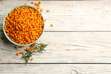 Photo of Fresh ripe sea buckthorn on white wooden table, flat lay. Space for text