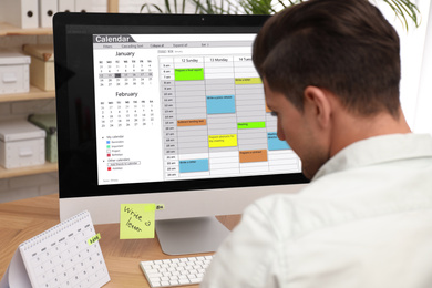 Photo of Man using calendar app on computer in office