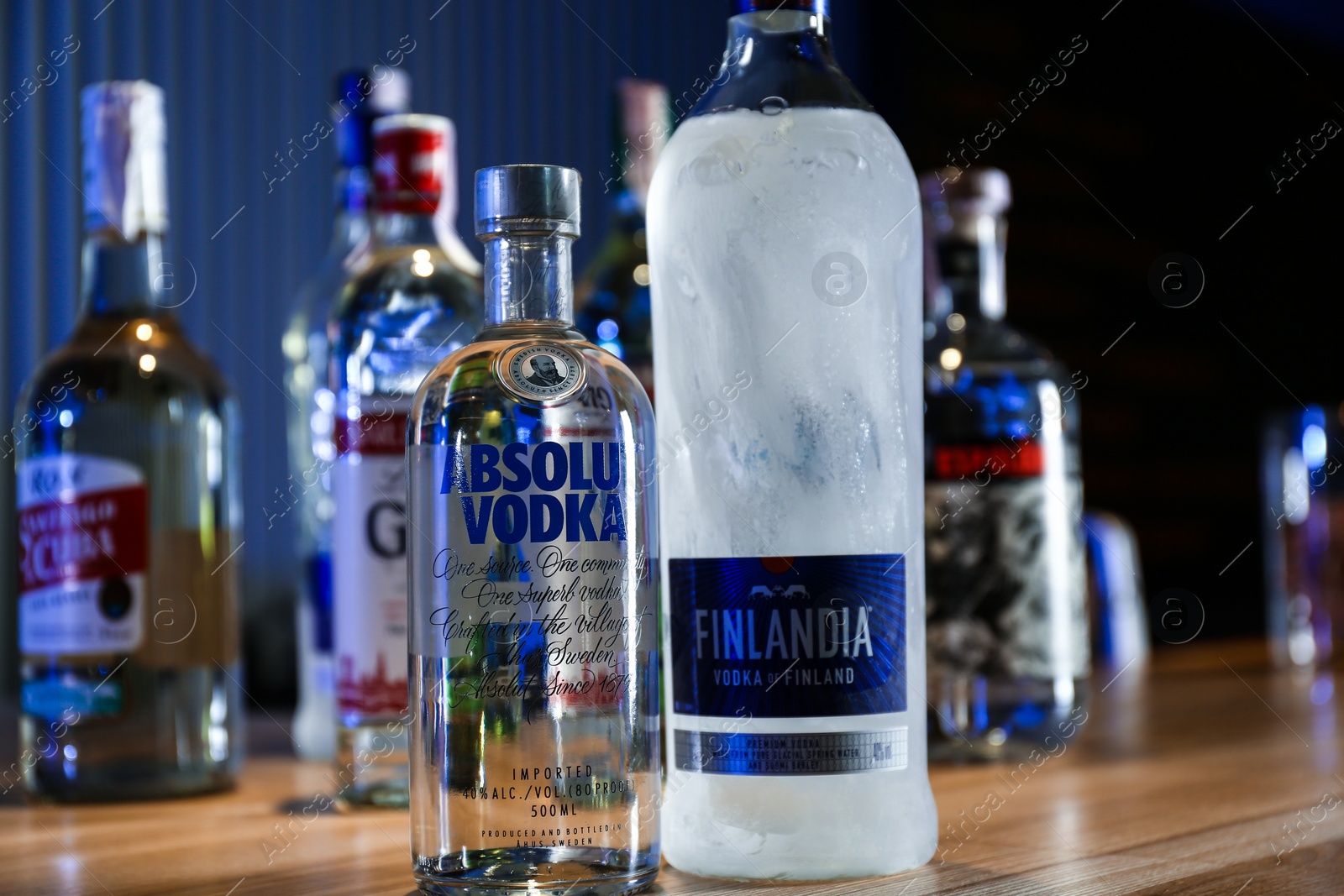 Photo of MYKOLAIV, UKRAINE - SEPTEMBER 24, 2019: Bottles of global vodka brands on wooden counter in bar