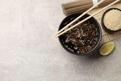 Photo of Tasty buckwheat noodles (soba) with sauce served on light grey table, flat lay. Space for text