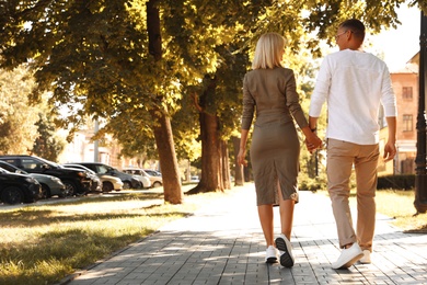 Photo of Happy couple walking along city street on summer day