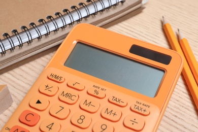 Photo of Calculator, notebook and pencils on wooden table, closeup. Tax accounting