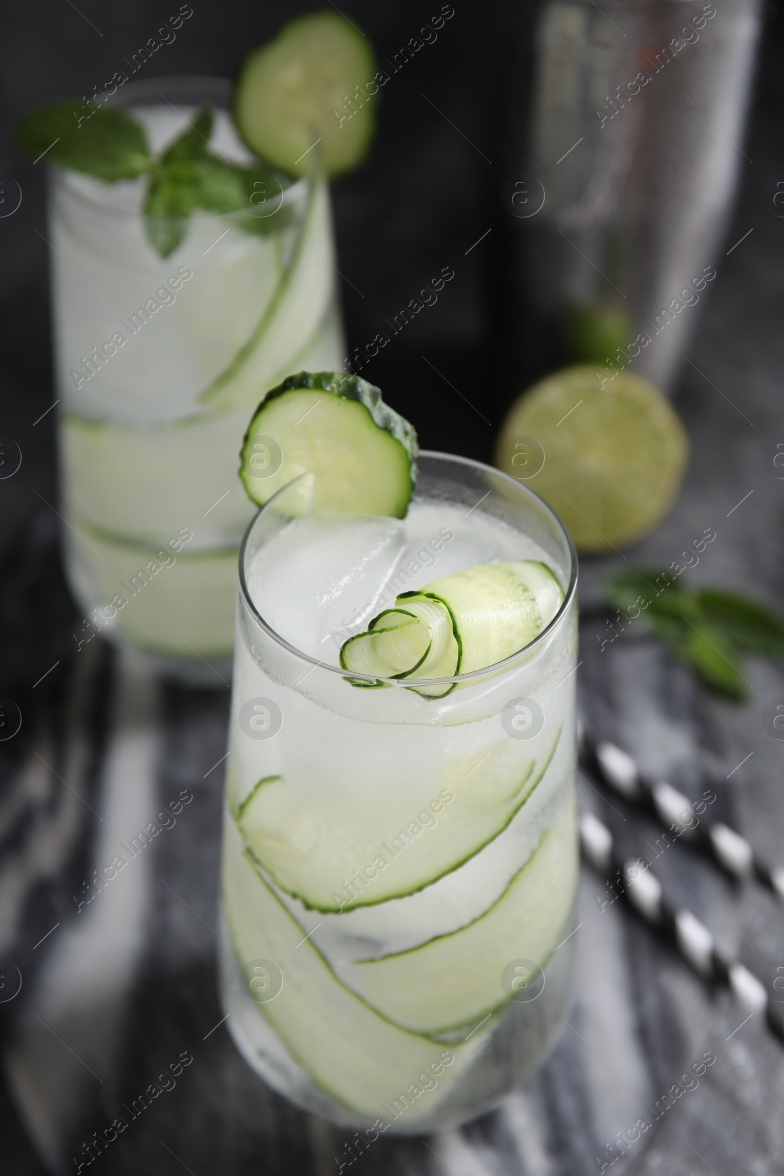 Photo of Refreshing cucumber water with ice on dark grey table, closeup