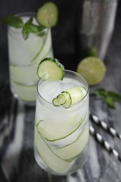 Photo of Refreshing cucumber water with ice on dark grey table, closeup
