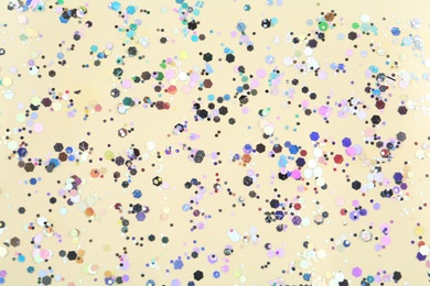 Photo of Shiny glitter on beige background, top view