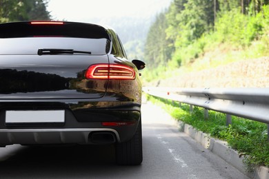 Modern black car on asphalt road outdoors, space for text