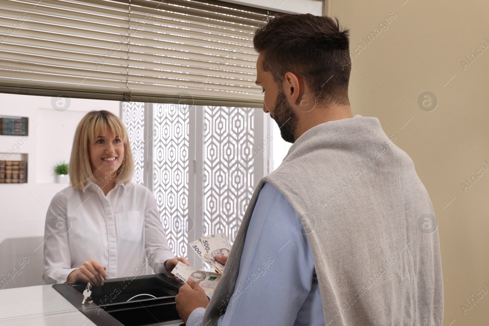 Photo of Man with money at cash department window in bank. Currency exchange