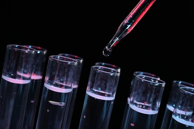 Photo of Dripping reagent into test tube on black background, closeup. Laboratory analysis